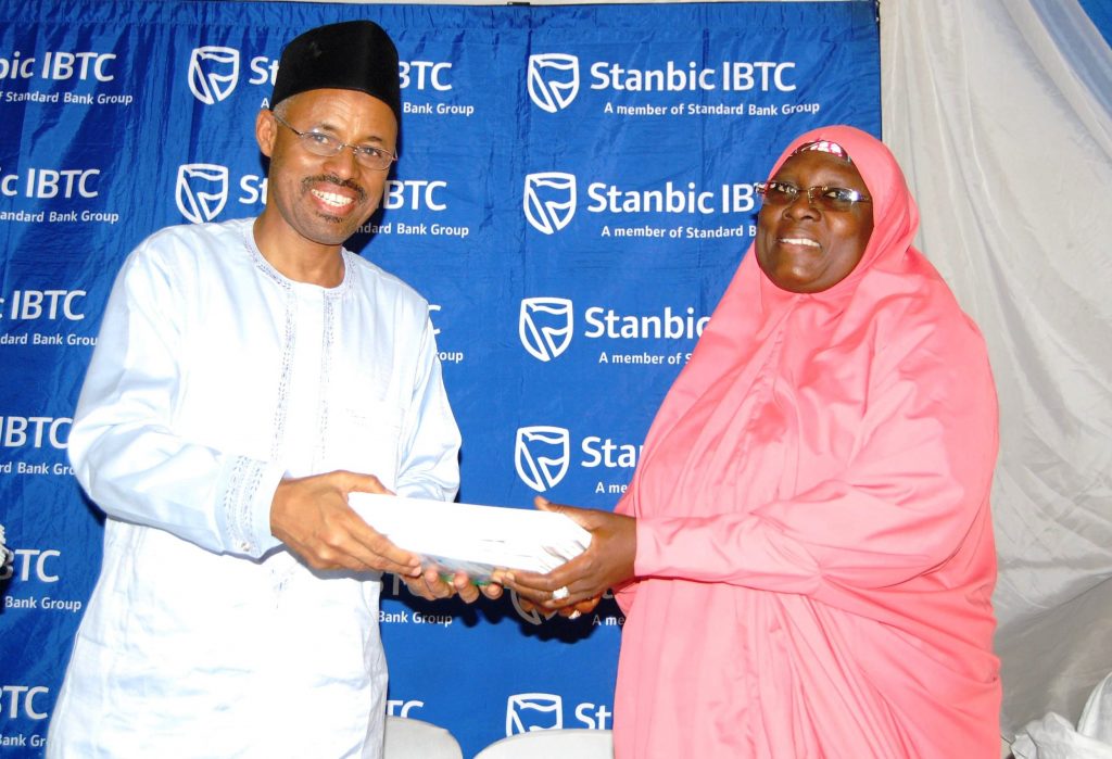 Head, Public Sector Group, Mr. Yusufu Modibbo, Stanbic IBTC Bank, presenting financial literacy books from the Central Bank of Nigeria to the Principal, Government Girls Secondary School, Maimuna Gwarzo, Tudun Wada, Kaduna State, Hajiya Hassana Usman, during an event organised by Stanbic IBTC to mark the 2016 Financial Literacy Day at GGSS Kaduna on Thursday, 17 March, 2016.